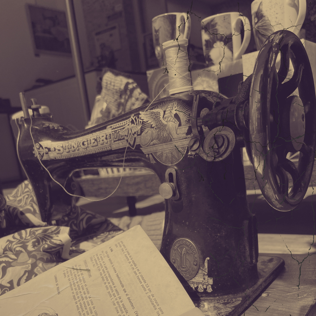 Máquina de coser vintage Singer con detalles dorados, rodeada de telas y tazas.