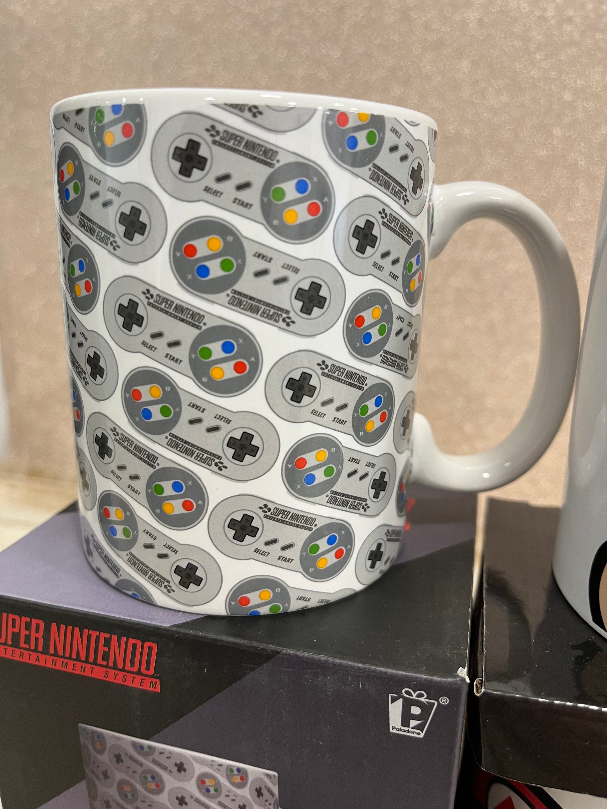 Taza de mandos Super Nintendo sobre una caja negra