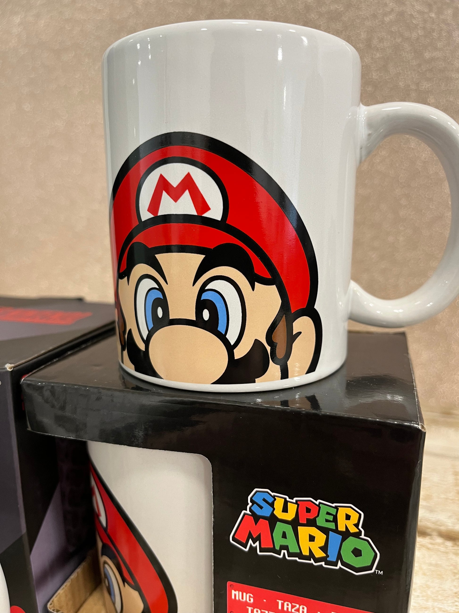 taza Super Mario sobre caja negra con logo Super Mario