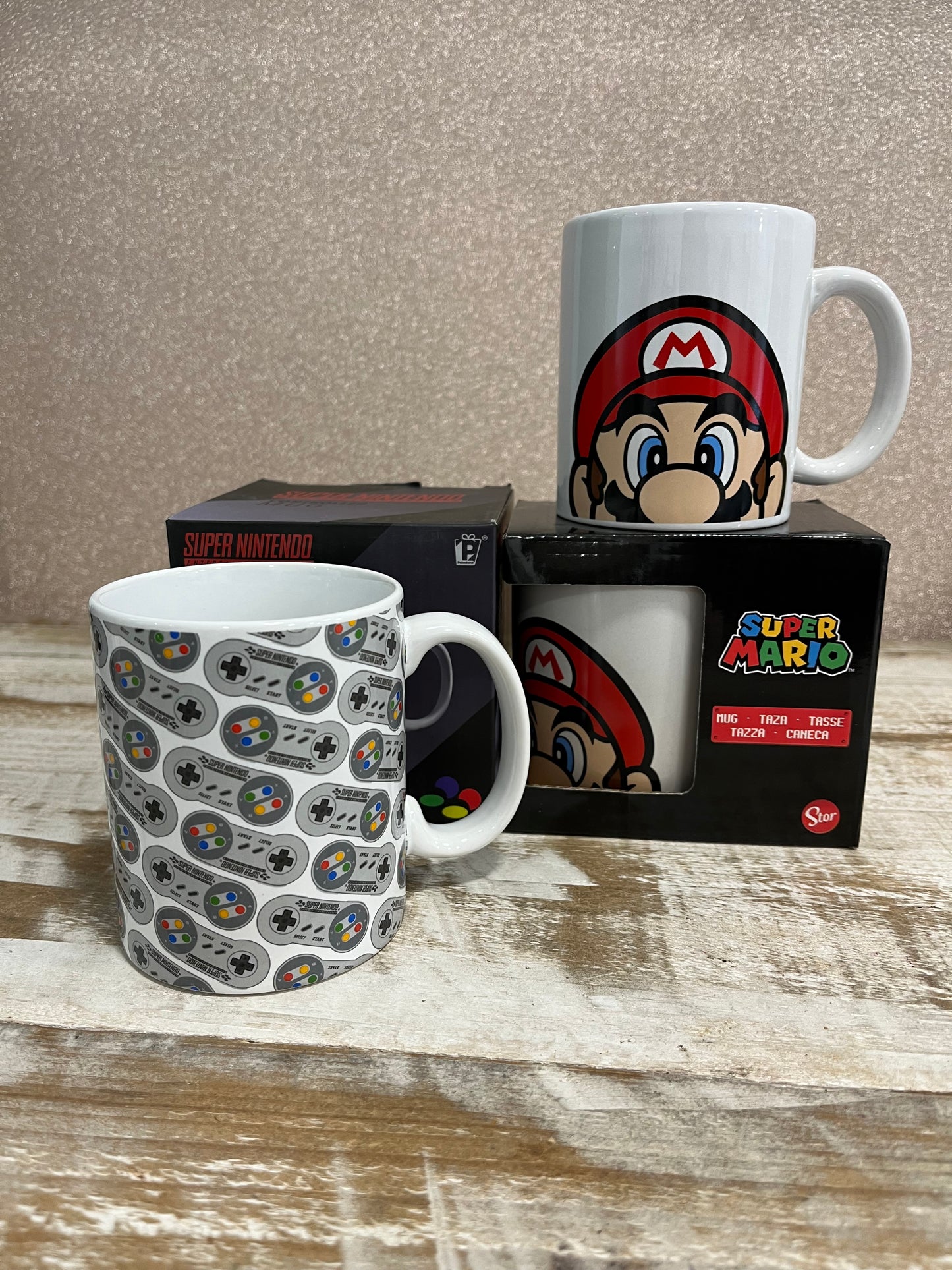 Tazas de Super Mario y mandos de Super Nintendo sobre una mesa de madera.