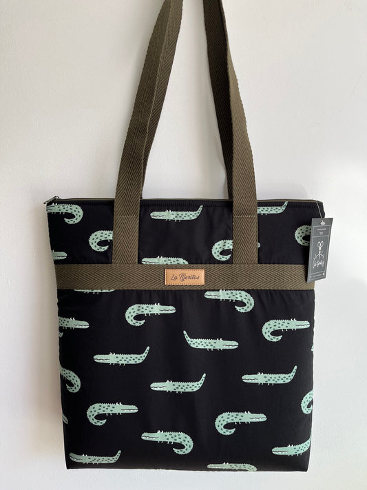 Bolso negro  con estampado de cocodrilos verdes, con ojos saltones y dientecitos. Correas verde militar a contraste.