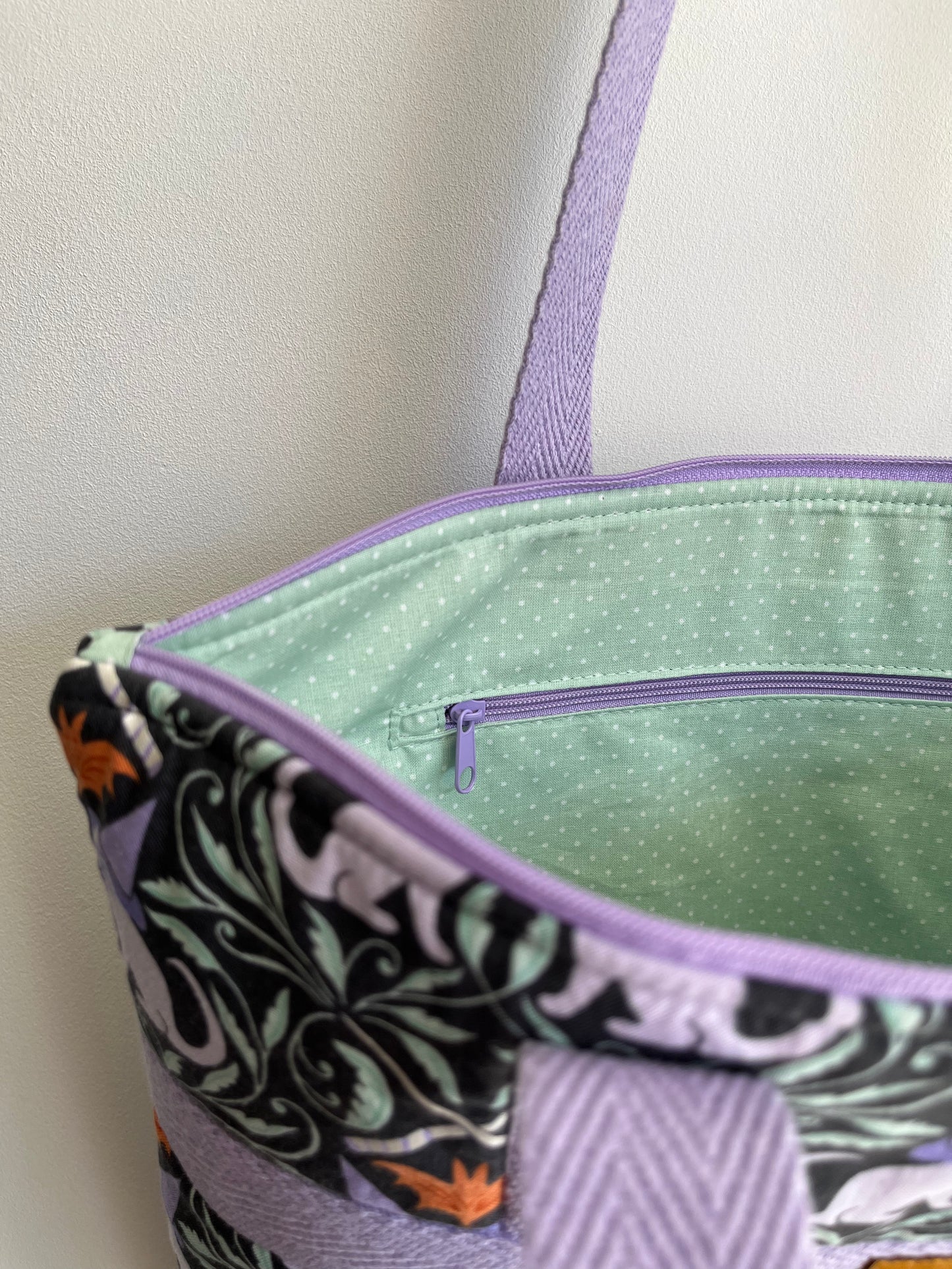 Detalle interior del bolso donde se ve el forro de color verde agua con topitos blancos.